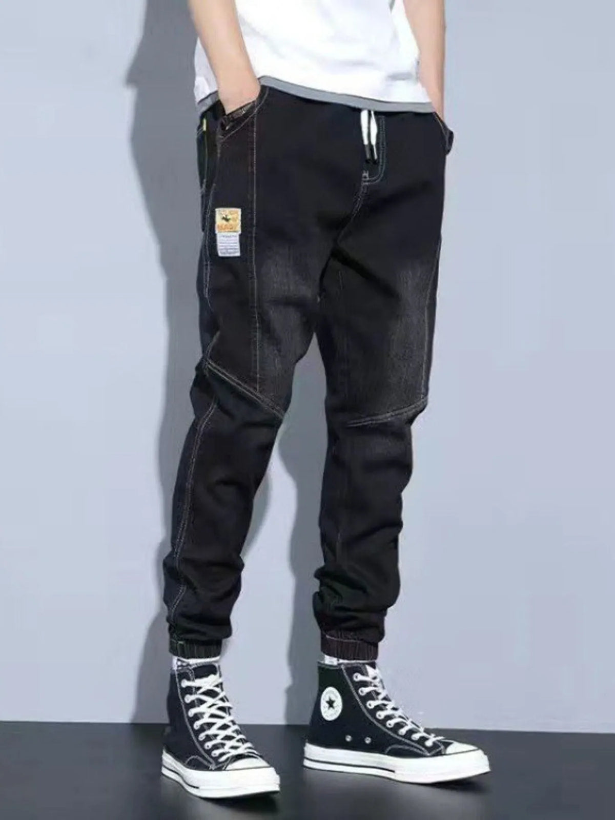 Men's washed black drawstring jeans with pockets and cuffed jogger hems.