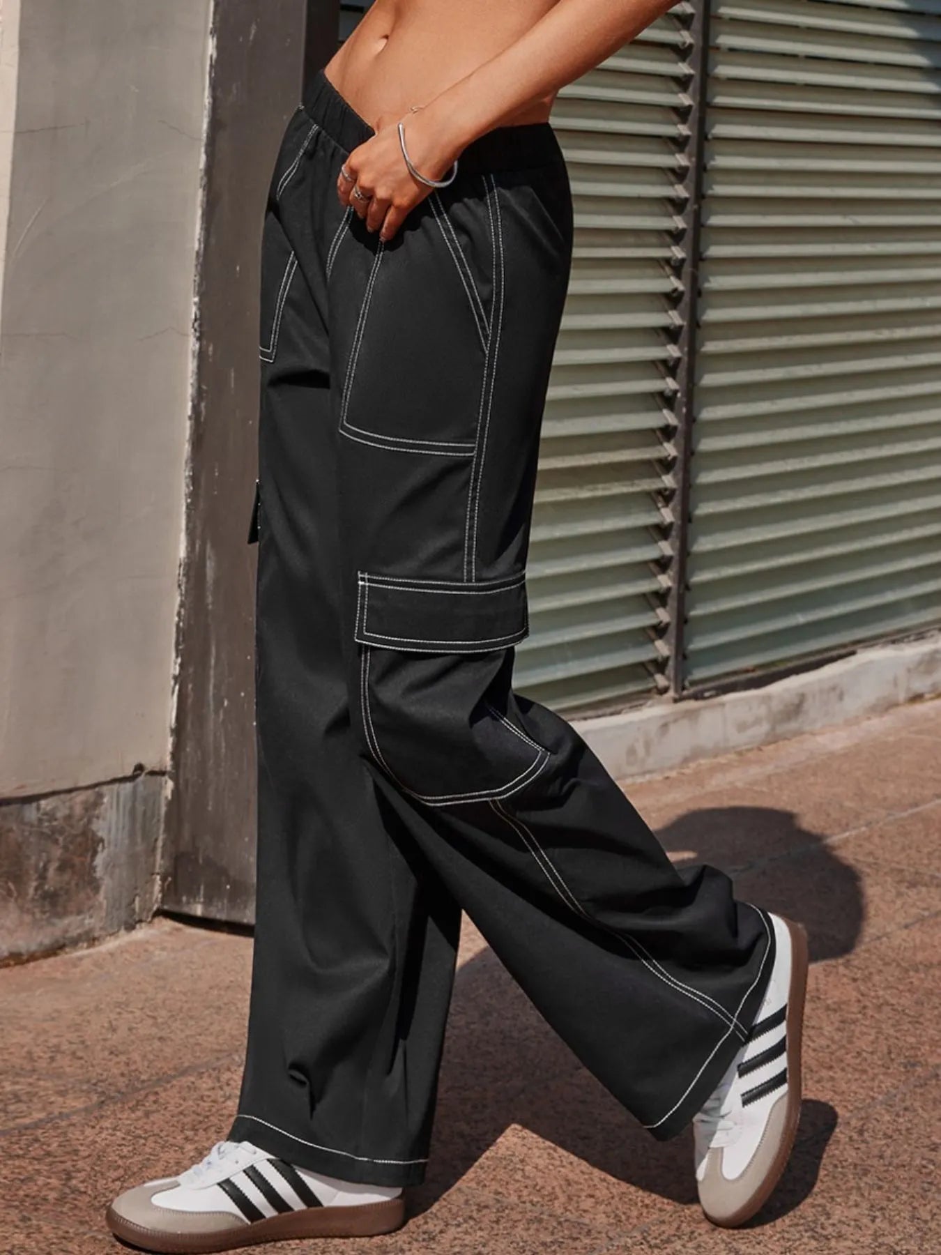 Black wide-leg pants with cargo-style flap pockets and contrast-stitched seams
