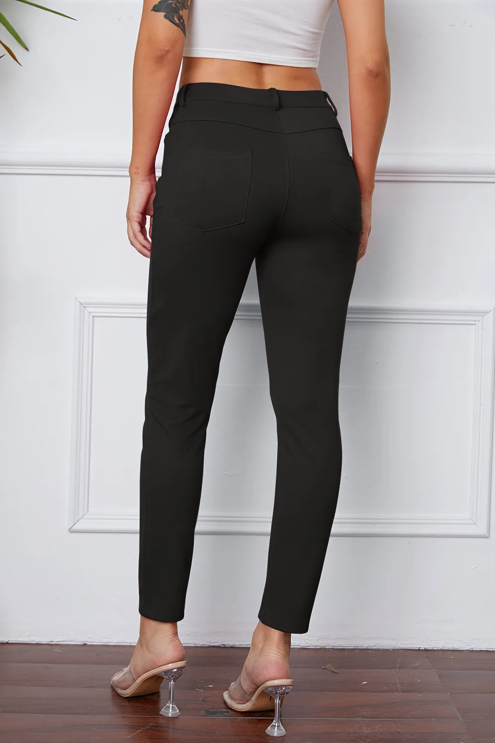 Stretchy black pants, rear view, with button waistband and slim ankle-length leg