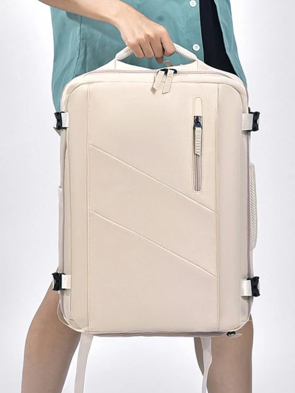Beige backpack bag held by a person’s hand, showing front zip and side straps