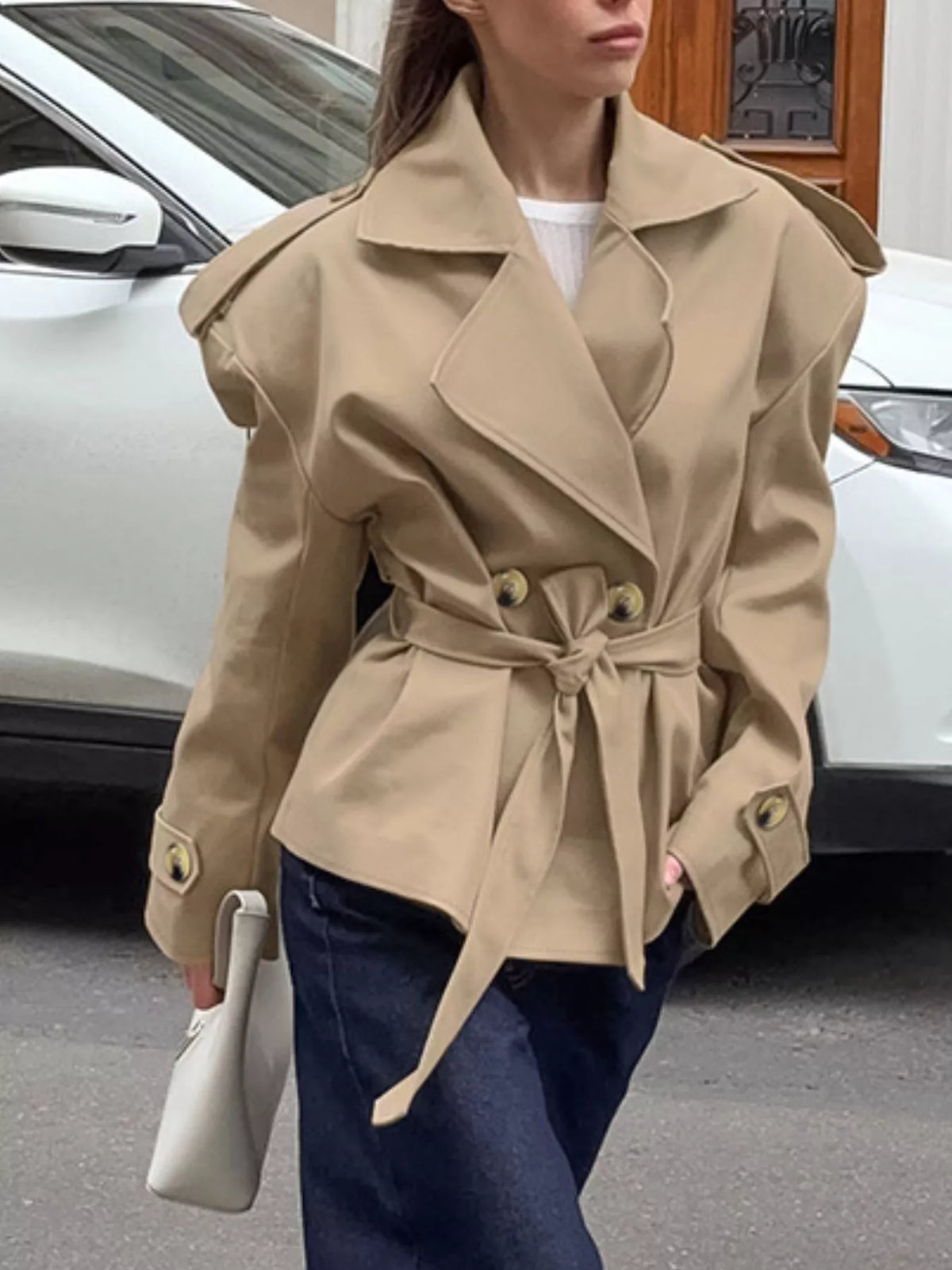 Khaki double-breasted belted trench coat, 3/4 view with waist tie and cuff buttons