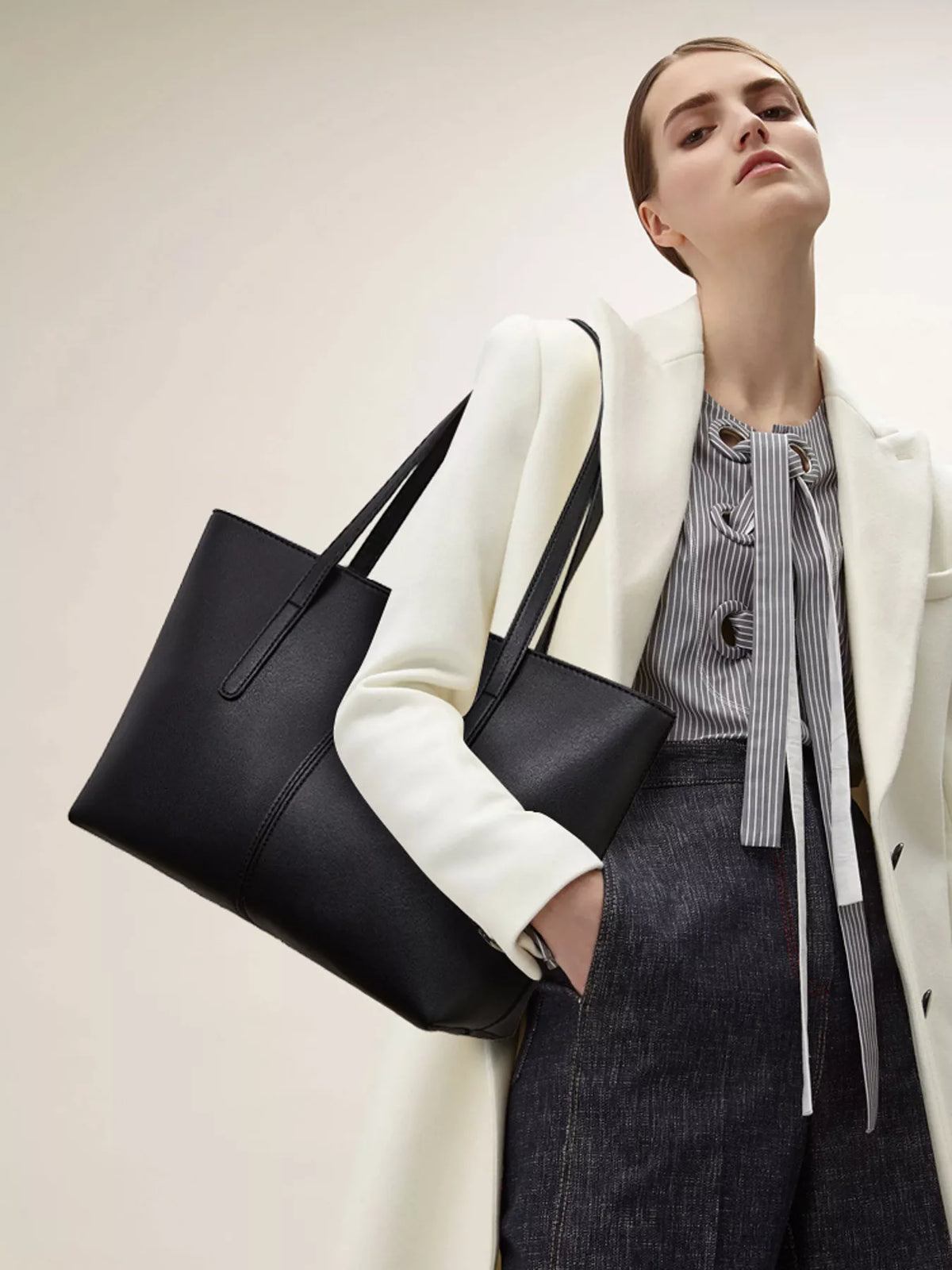 Black medium vegan leather tote bag, angled view, with two side handles