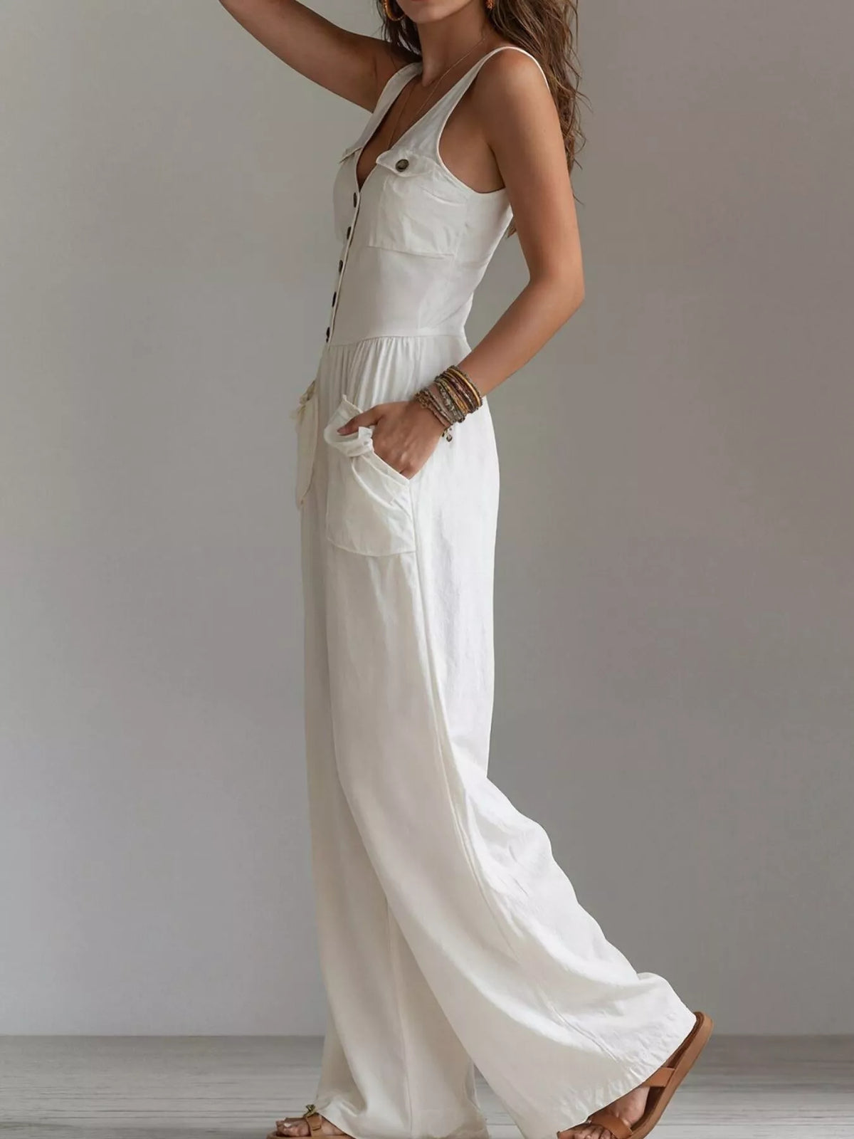 White sleeveless jumpsuit with button placket, chest pocket, gathered waist, wide leg