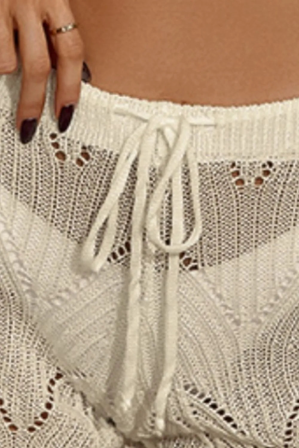 White cutout swim shorts close-up: crochet knit, drawstring waist, eyelet pattern