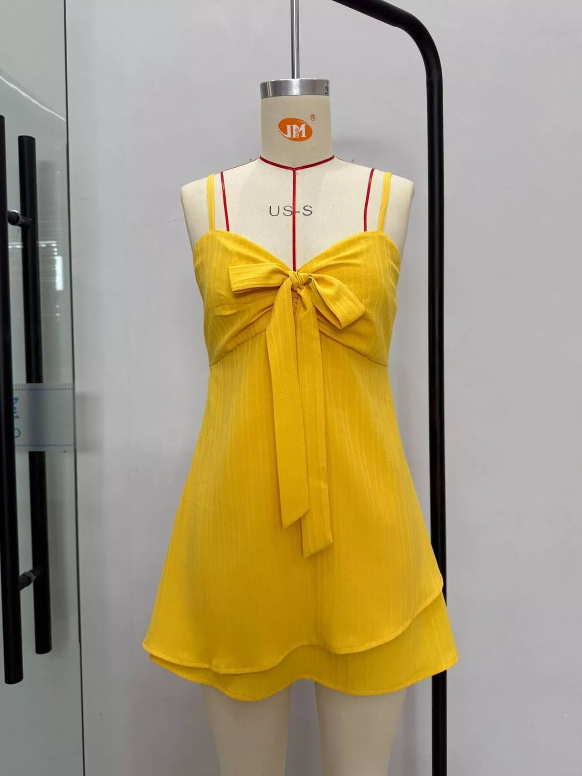 Yellow spaghetti strap bow-front mini dress on mannequin, V-neck and flared skirt