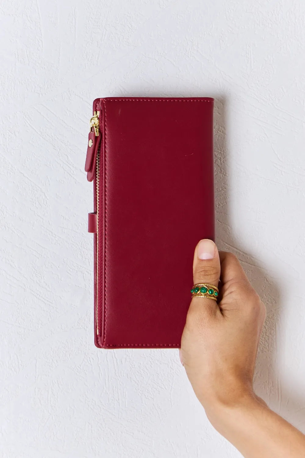 Red textured PU leather wallet with gold-tone zipper and front tab detail, hand-held.