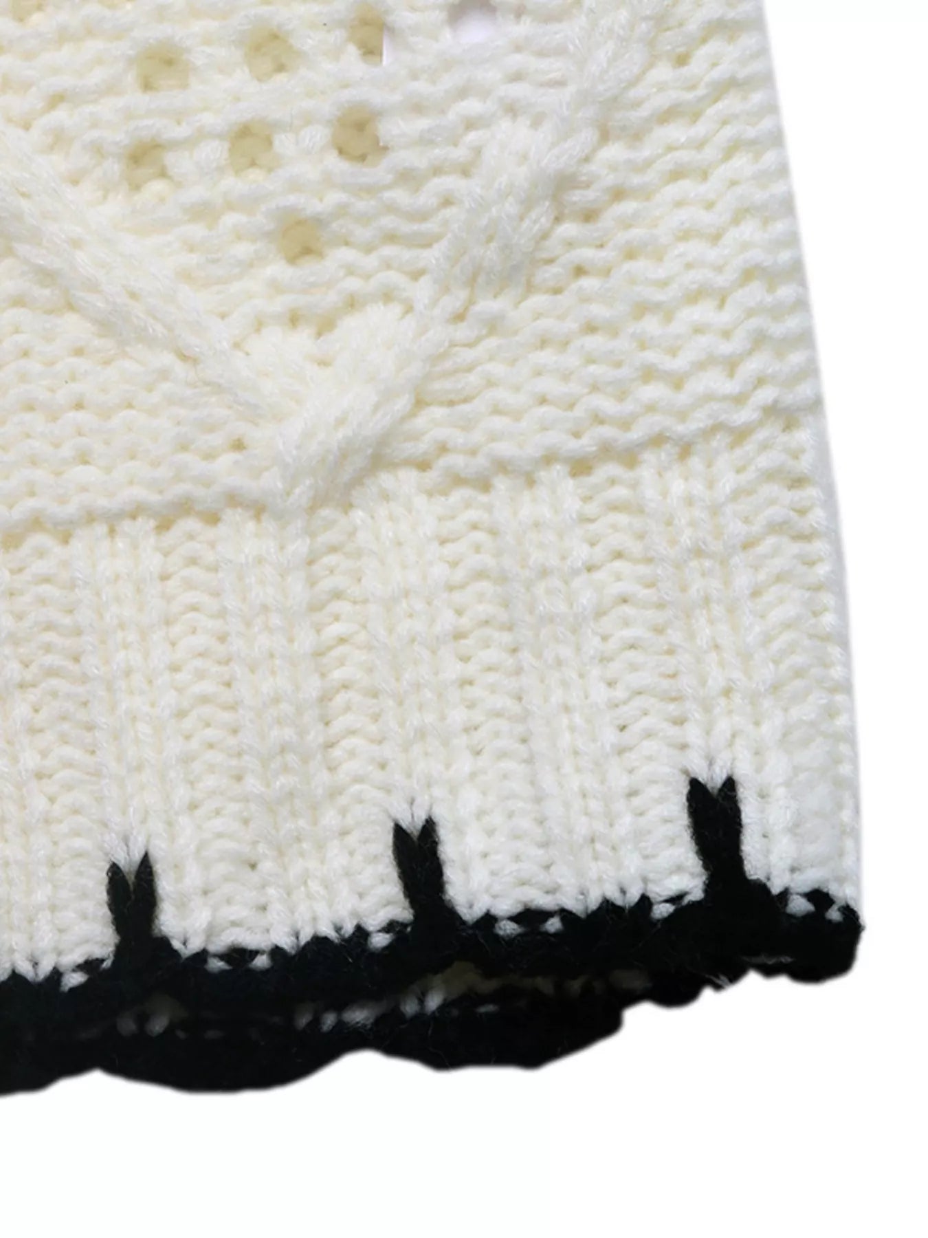 Ivory sweater hem with black striped trim and cable-knit texture