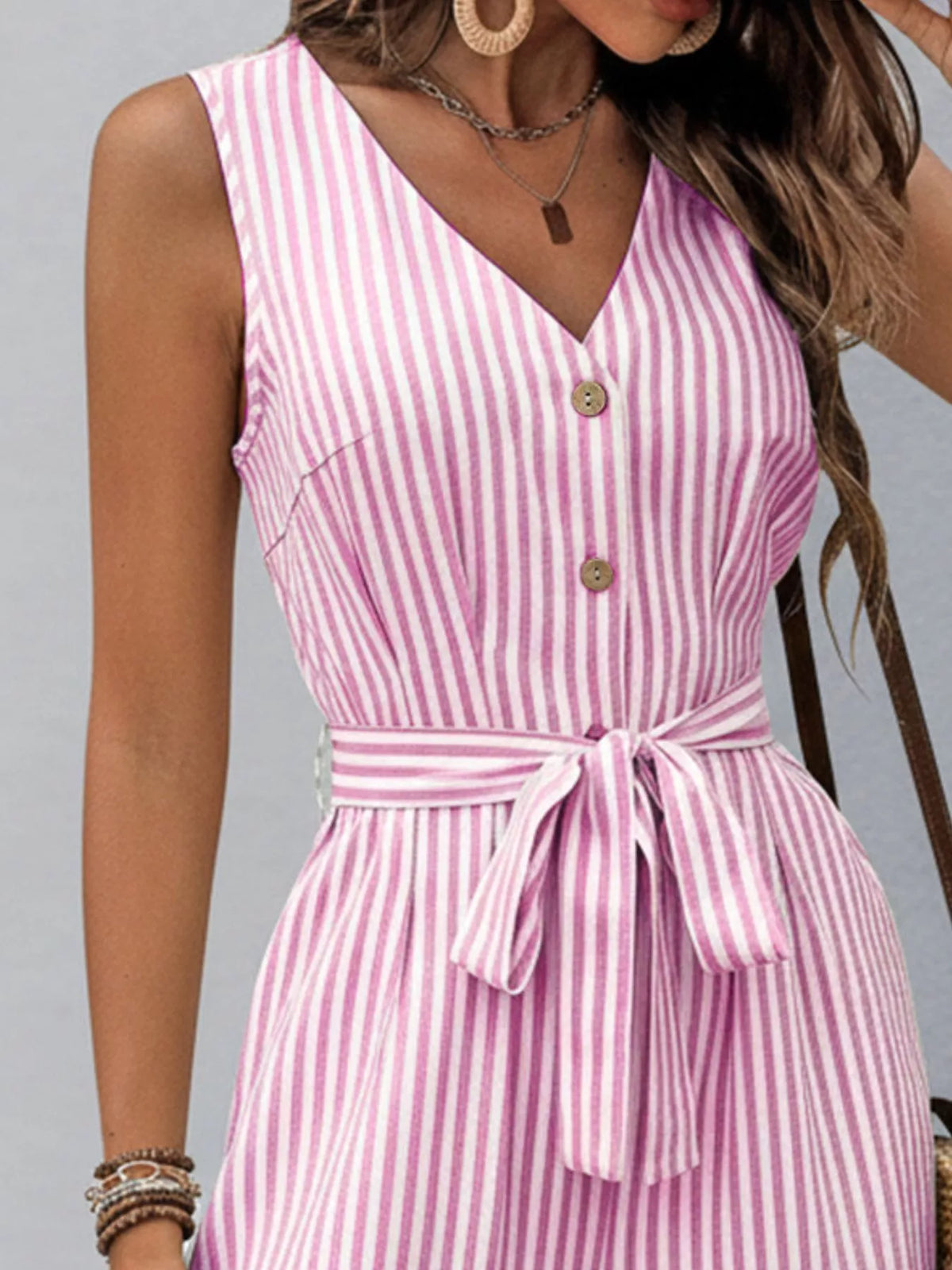 Pink striped V-neck sleeveless jumpsuit with button front and tied waist belt