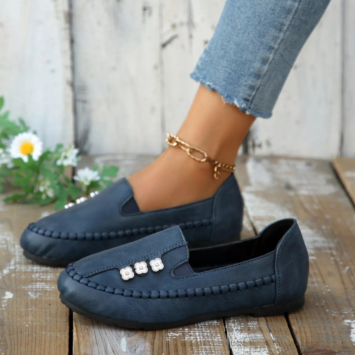 Dark blue round-toe slip-on flats with floral embellishment and stitched trim