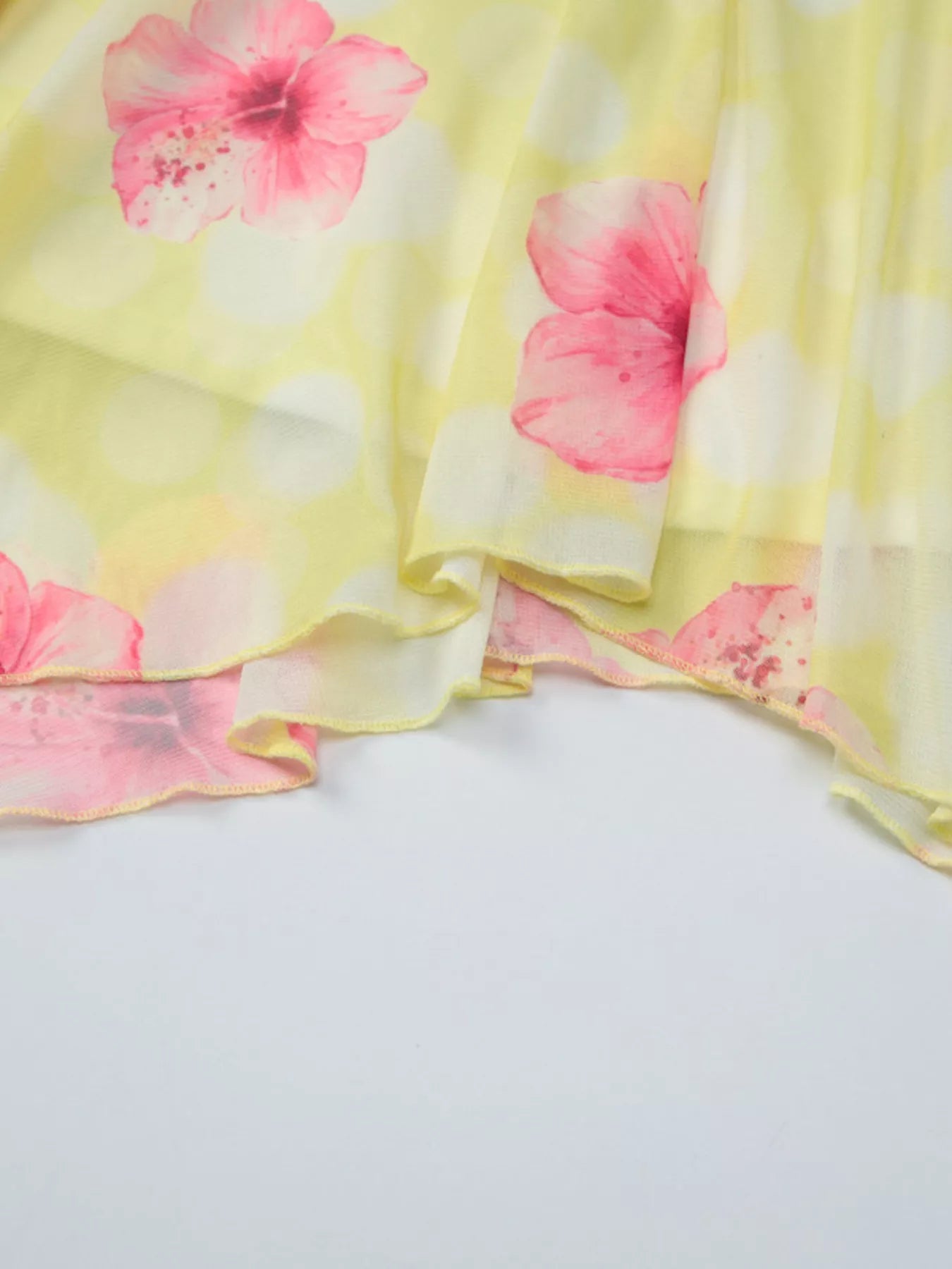 Close-up of yellow sheer skirt with pink flower print and ruffled layered edge
