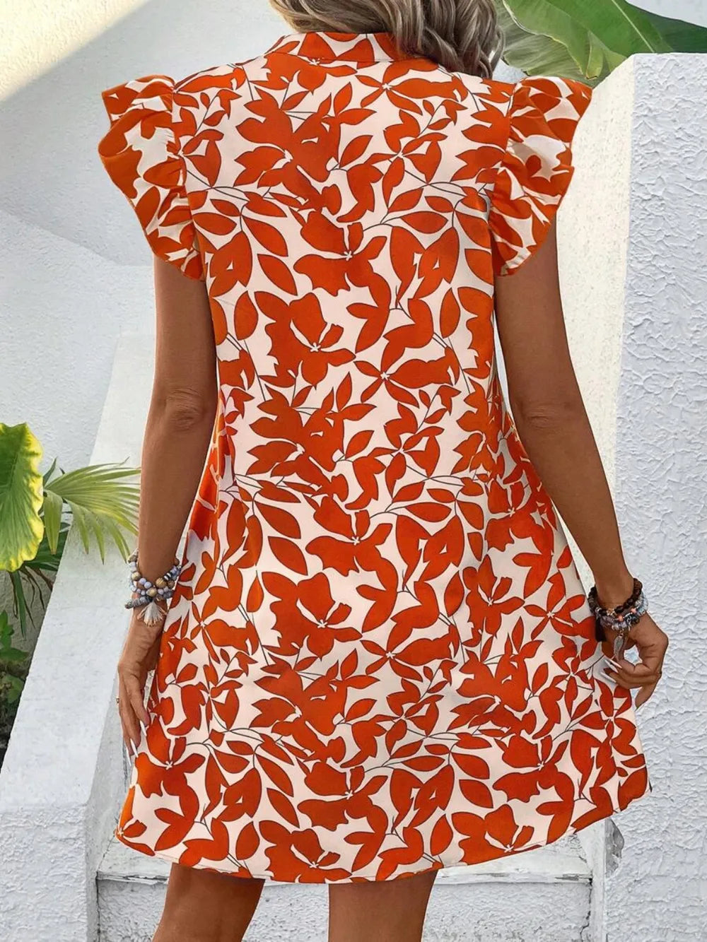 Printed Notched Cap Sleeve Mini Dress in orange floral print on white, back view.