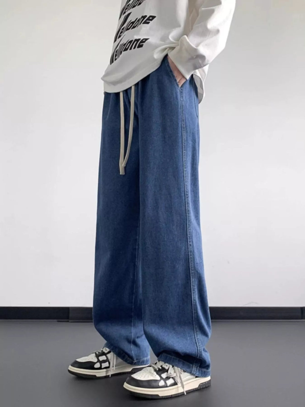 Blue washed denim jeans with loose fit, wide legs, and front drawstring ties