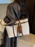 Off-white vegan leather tote bag with brown strap, buckle detail, and teddy keychain