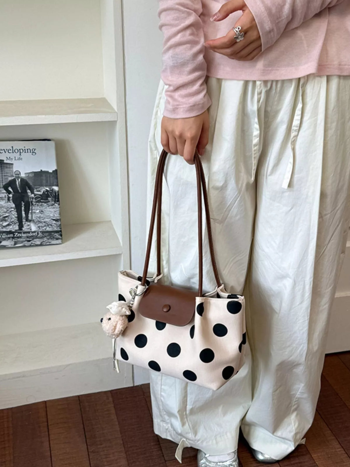 Polka dot shoulder tote with brown handles, black front flap, and bunny charm