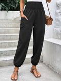 Black smocked high-rise jogger pants with side pockets and tapered ankle cuffs