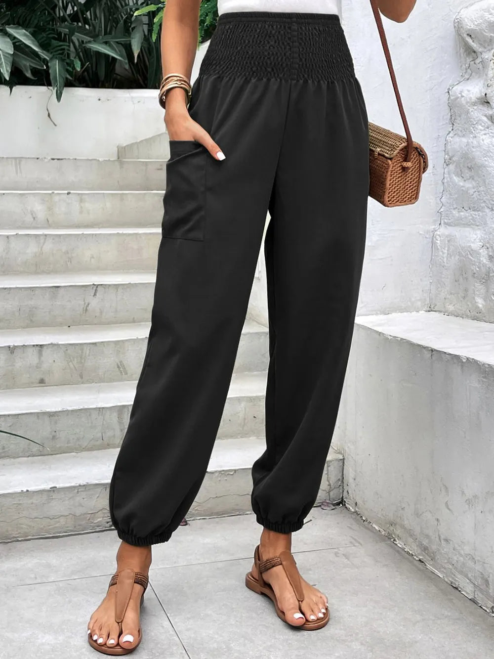 Black smocked high-rise jogger pants with side pockets and tapered ankle cuffs