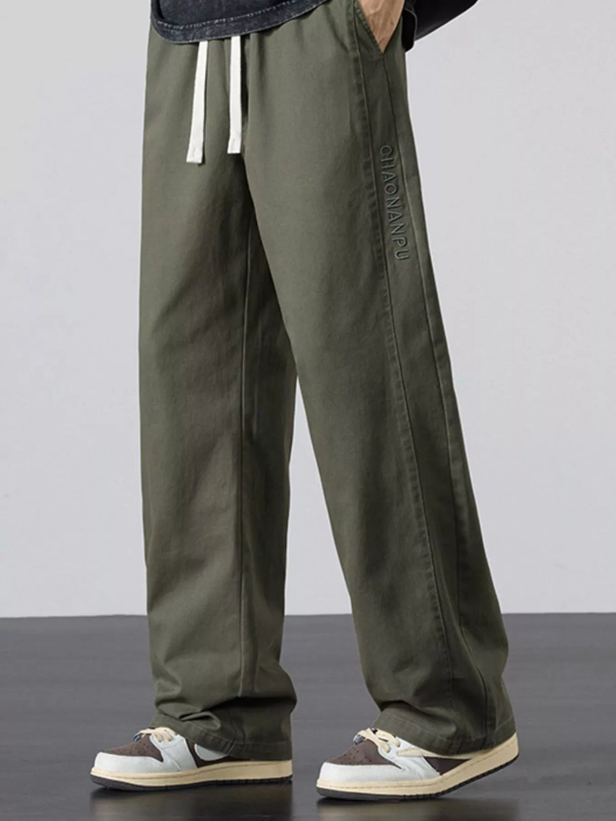Mens army green wide-leg pants featuring elastic waistband and white drawstring