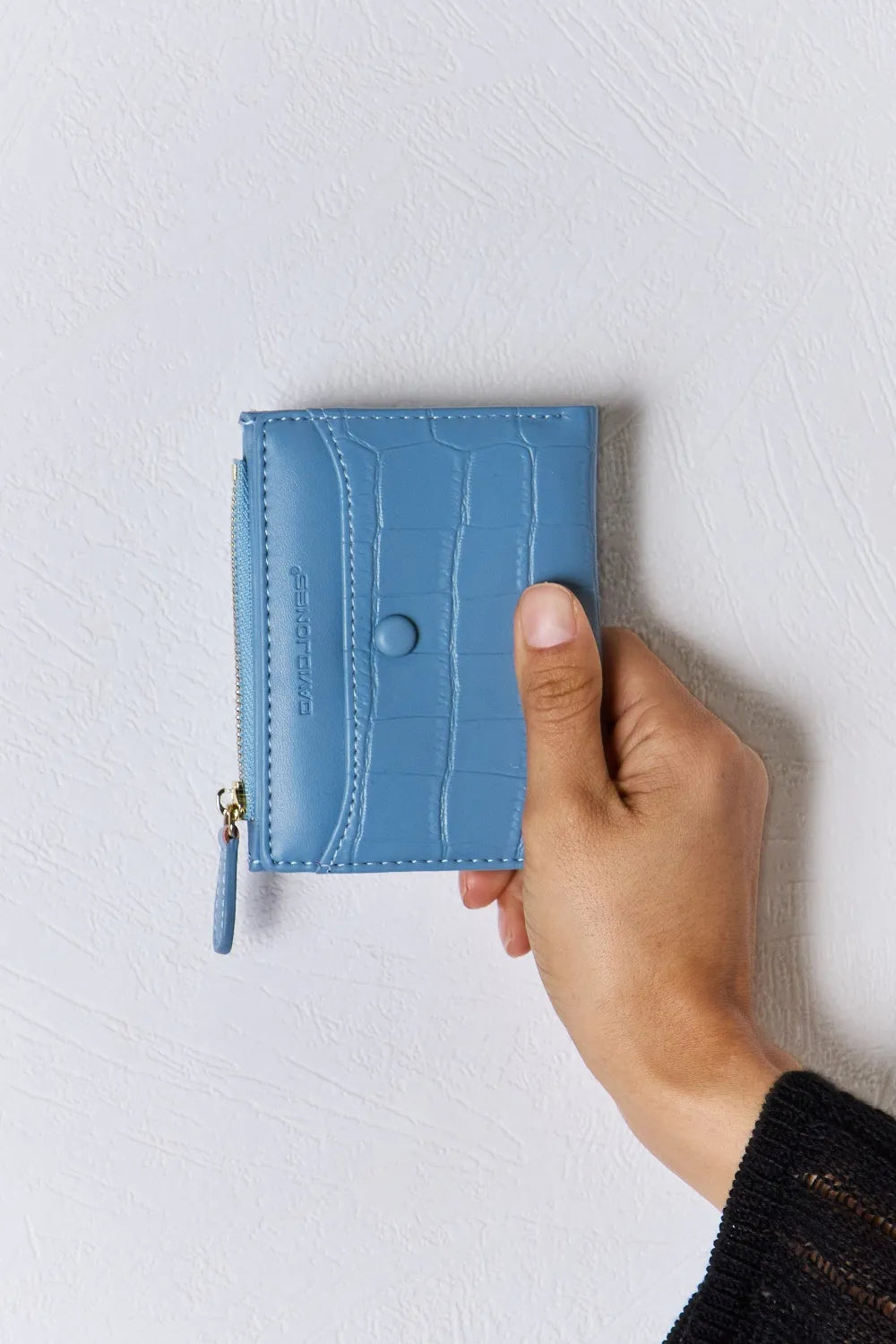 Blue textured vegan leather mini wallet with gold zipper, wrist strap, and snap button.