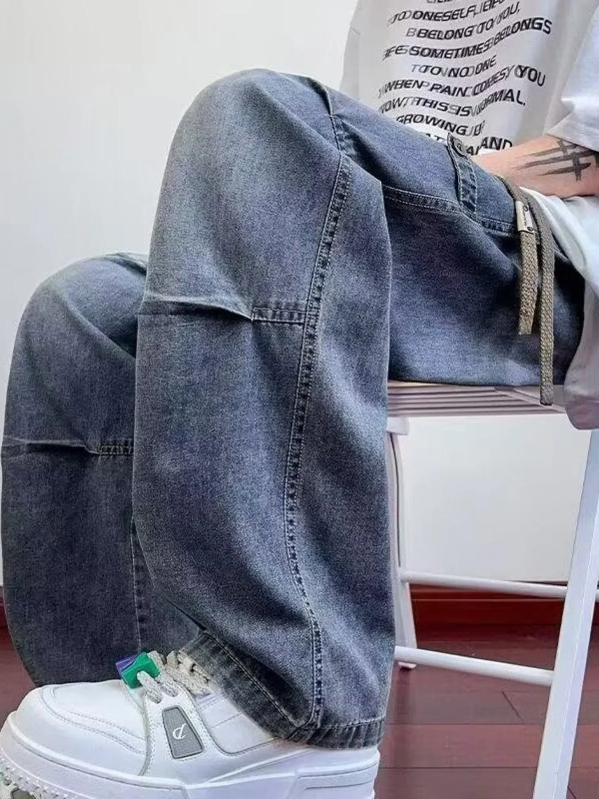 Men's wide-leg washed denim pants showing side view with patch pockets and drawstring tie