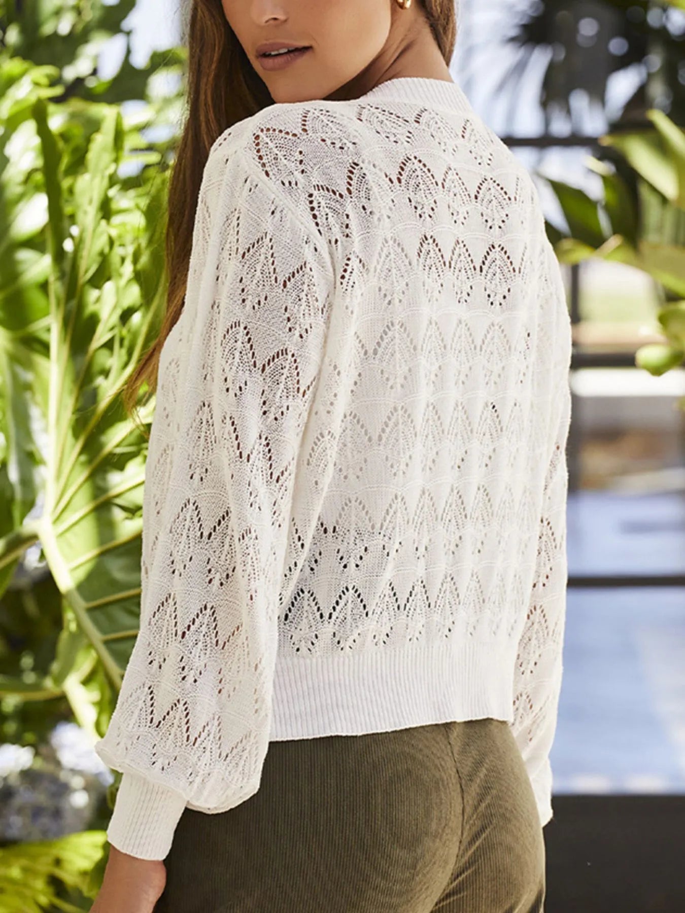 White openwork cardigan sweater with button front and long sleeves, side view