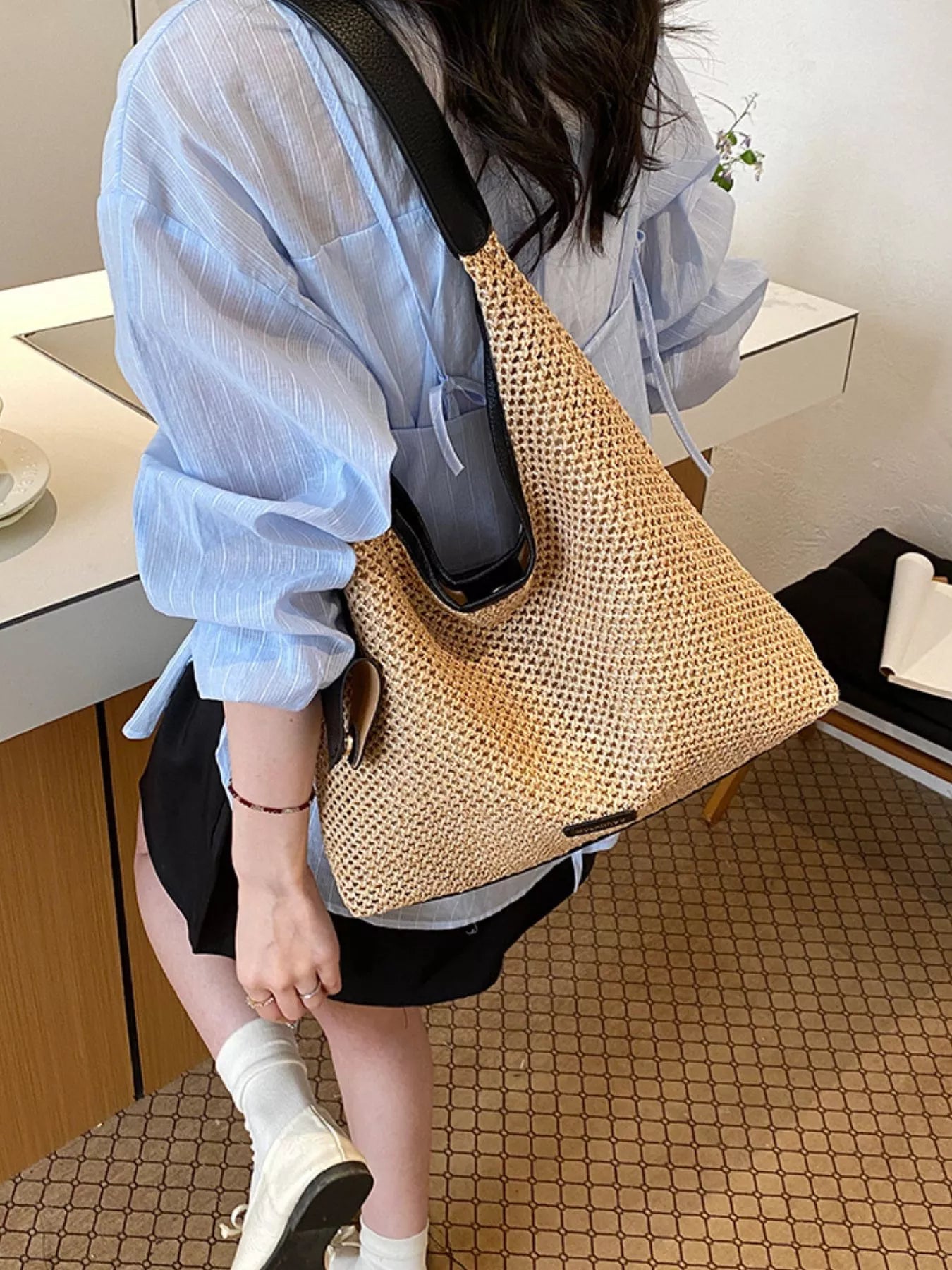 Camel woven straw shoulder bag with black strap, open top, and front pocket