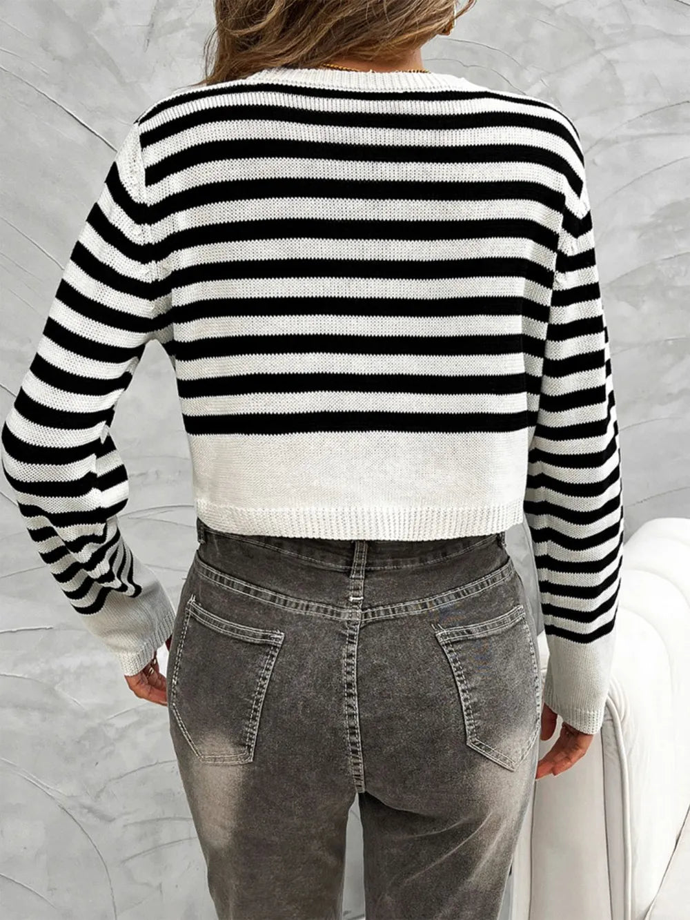 Back view of black and white striped knit cardigan, round crew neck, buttonless back