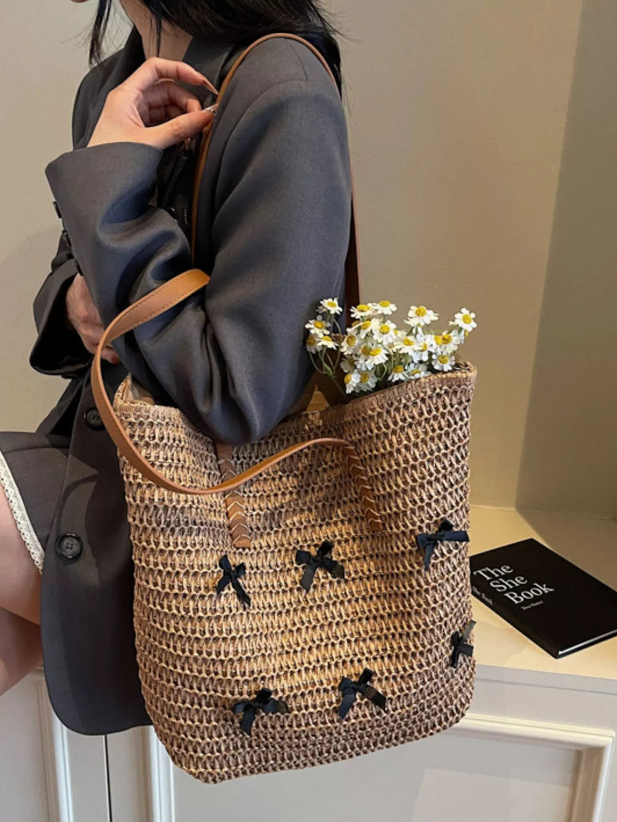 Caramel woven straw tote bag with bow applique pattern and flower bouquet inside
