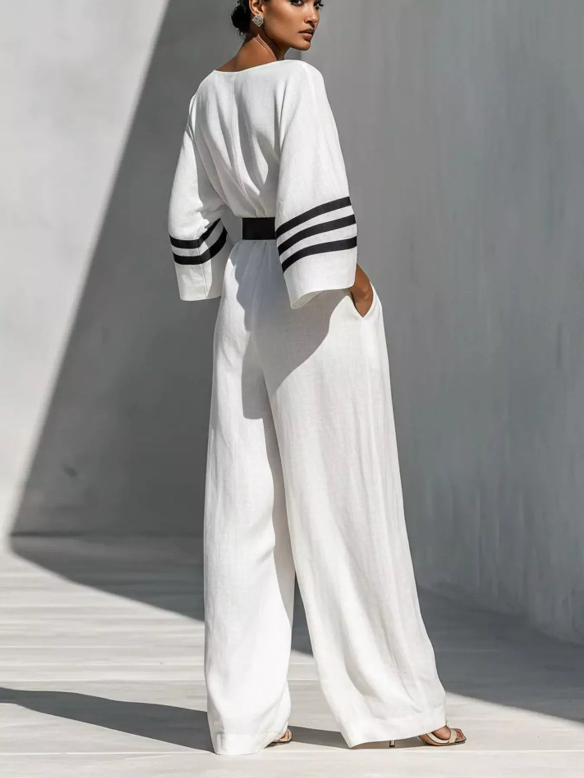 White wide-sleeve jumpsuit with striped cuffs and belted waist, full-length