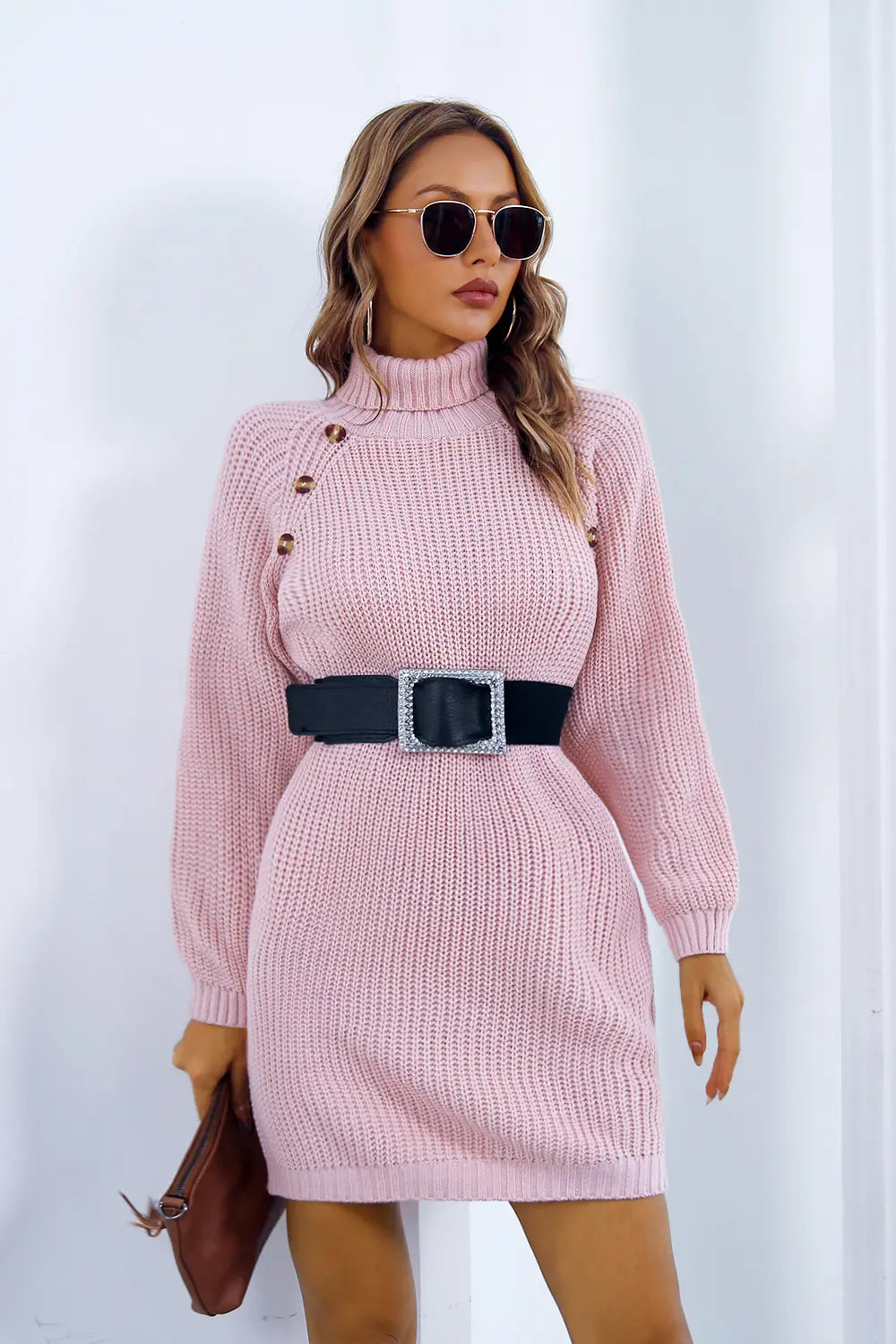 Pink knit turtleneck sweater dress with long sleeves, button placket and black belt