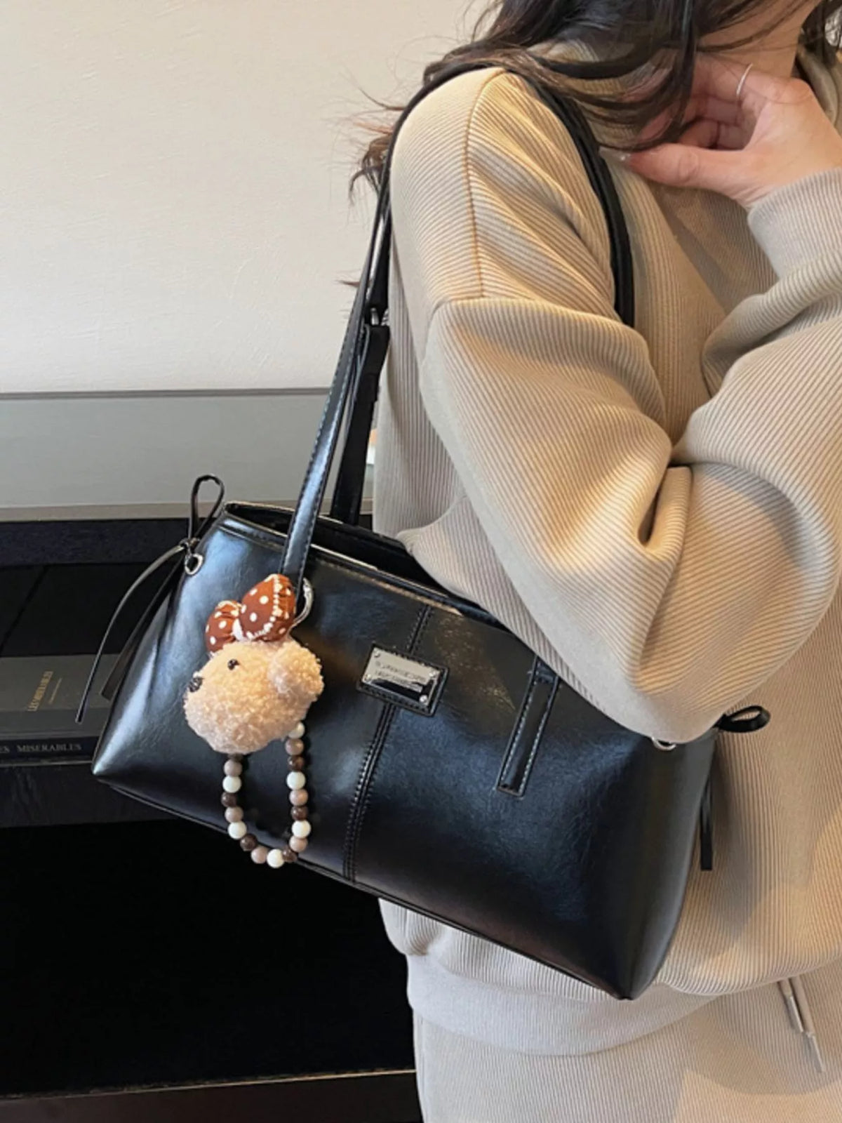 Black vegan leather medium shoulder bag with top handles and dangling teddy charm