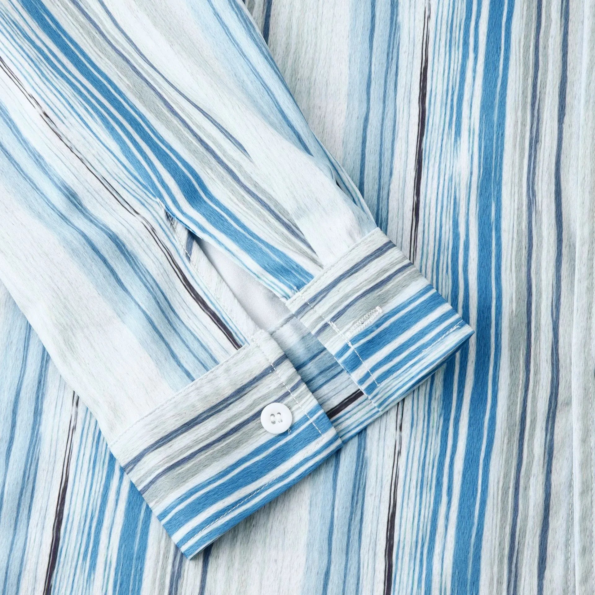 Long-sleeve button-up shirt cuff with pastel blue striped trim and white buttons