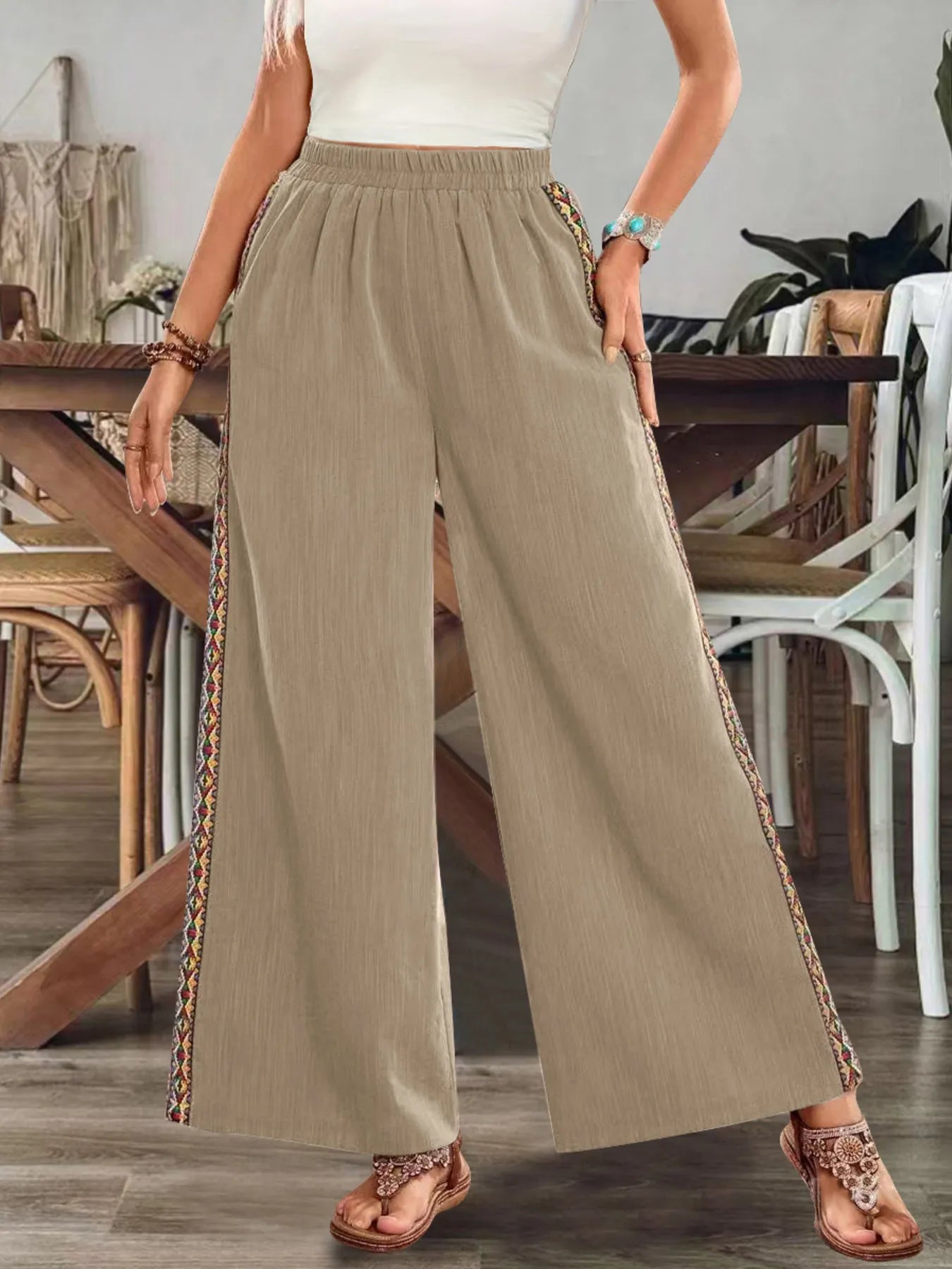 Beige wide-leg pants with elastic waist and embroidered side stripe, relaxed drape.