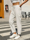 White elastic waist tapered pants with drawstring ties, relaxed ankle-length fit
