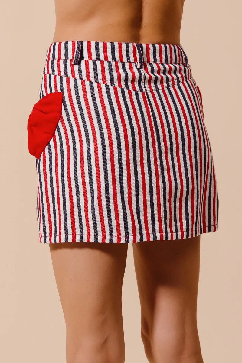 Striped denim mini skirt with red bow accent, buttoned waistband, and side pocket