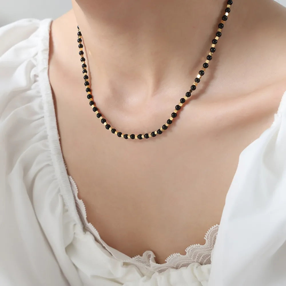 Agate beaded necklace with black beads and gold-tone accents, layered drape