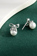 Silver bow stud earrings with round pearl drops, polished metal hardware.