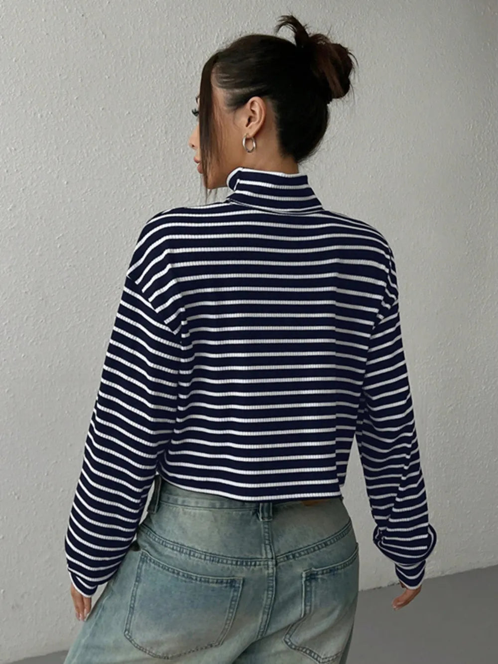 Back view of navy and white striped cropped turtleneck long-sleeve top