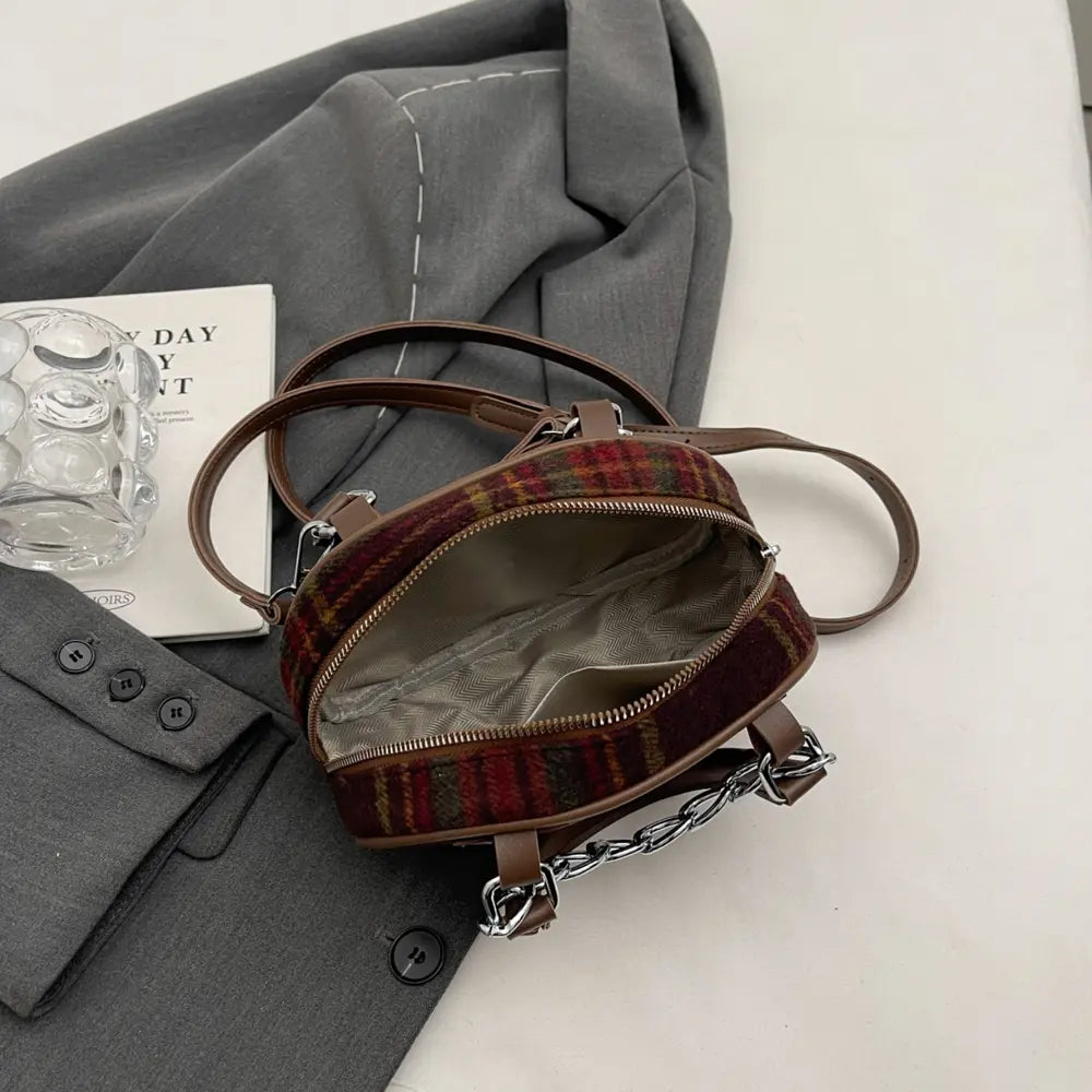 Plaid crossbody bag opened view with brown trim, zipper opening, and chain strap