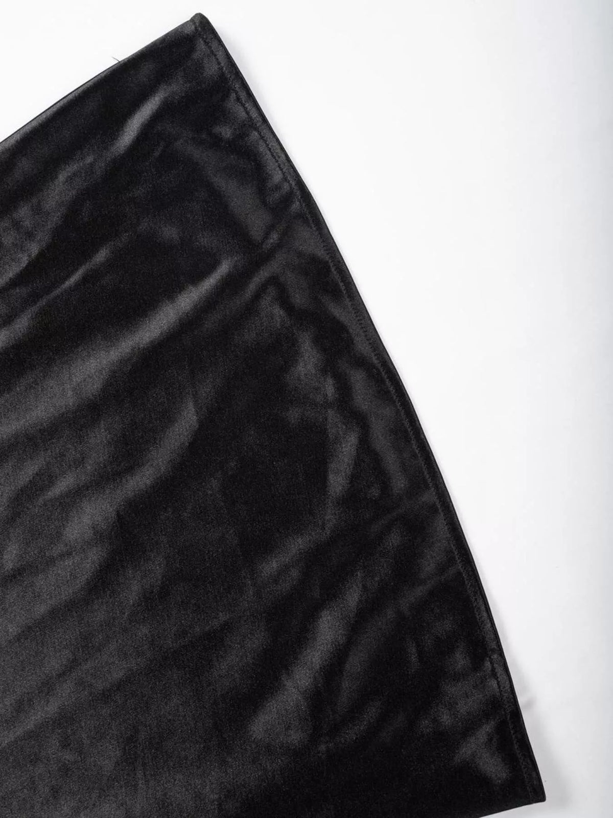 Black satin skirt fabric close-up showing subtle wrinkles and edge stitching