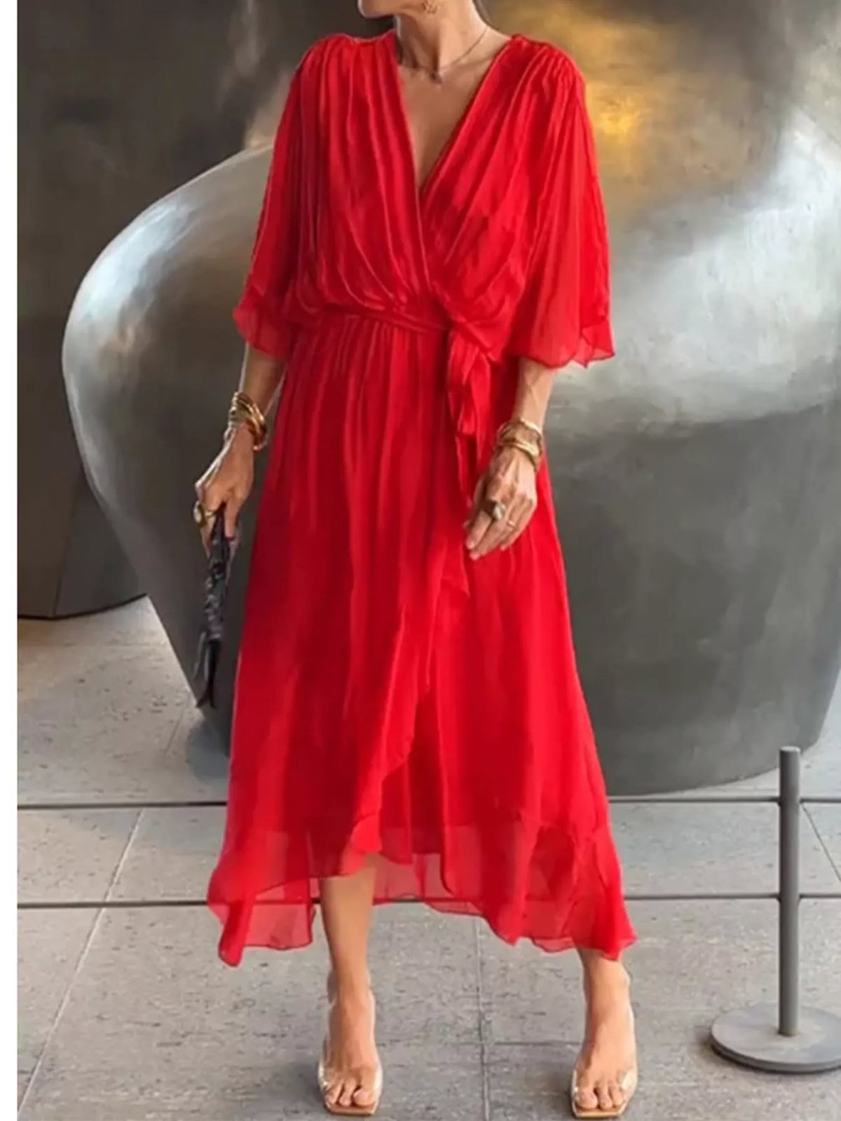 Red ruched wrap dress with batwing sleeves and waist tie; flowing midi silhouette.
