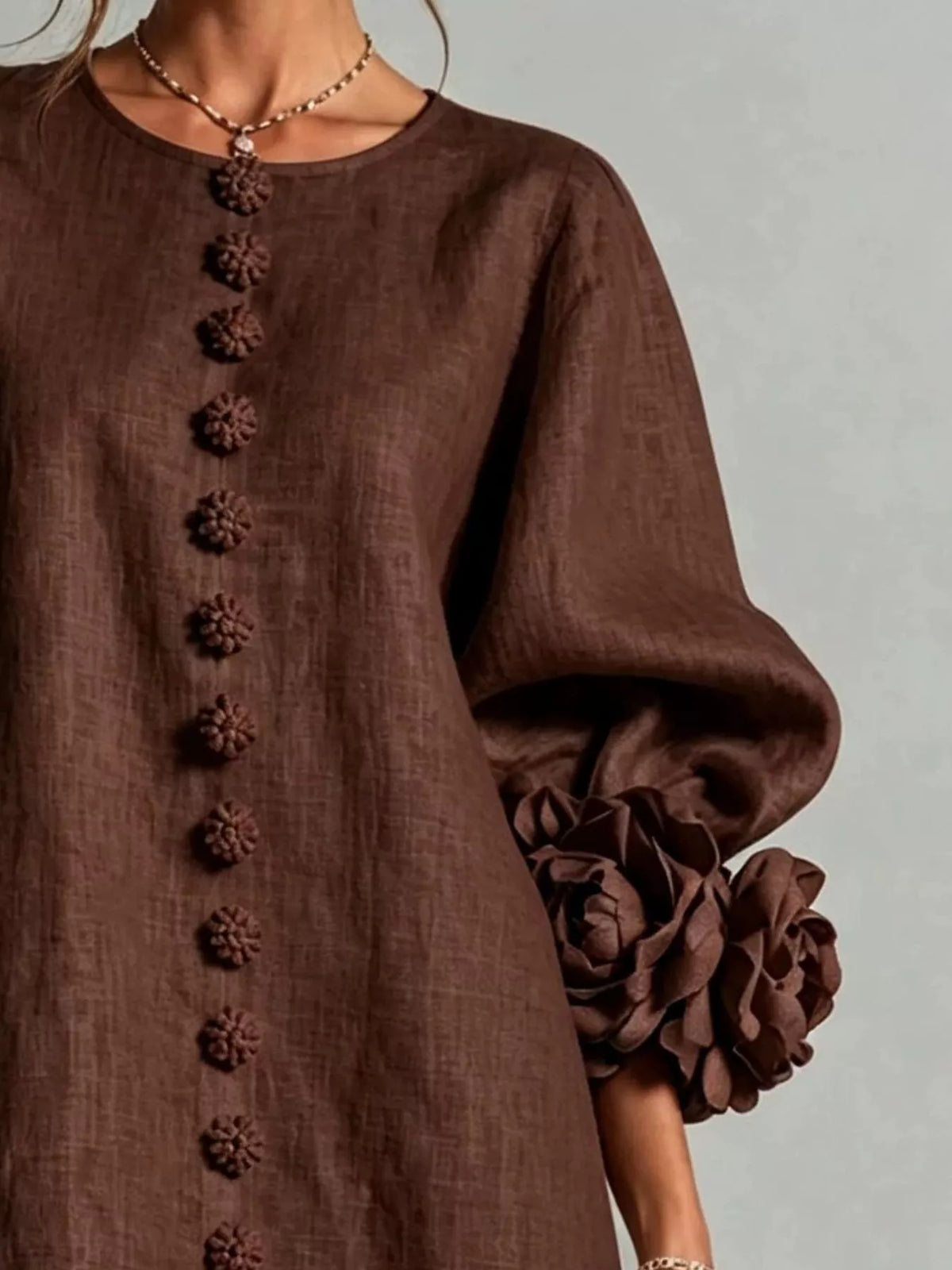 Brown polyester dress close-up with round neck and vertical 3D floral button trim
