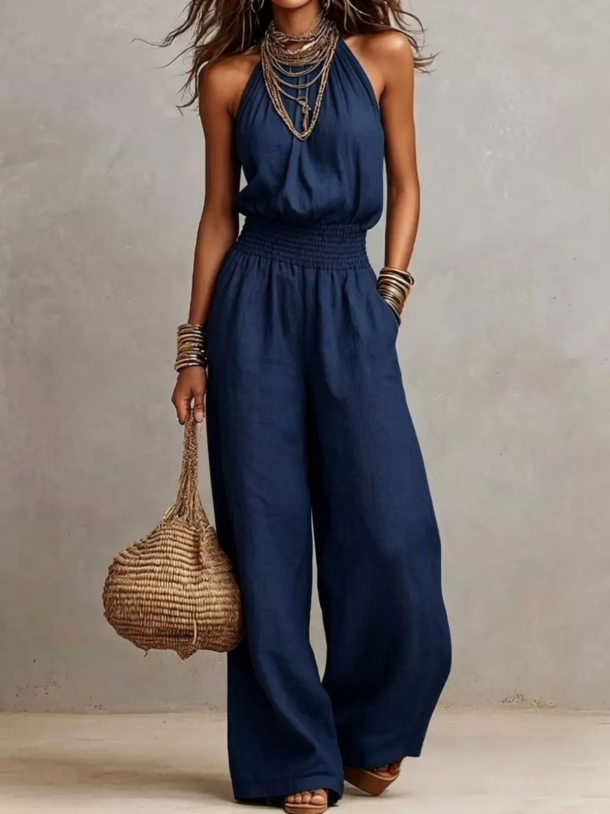 Navy smocked halter neck wide-leg jumpsuit with gathered waist and sleeveless bodice.