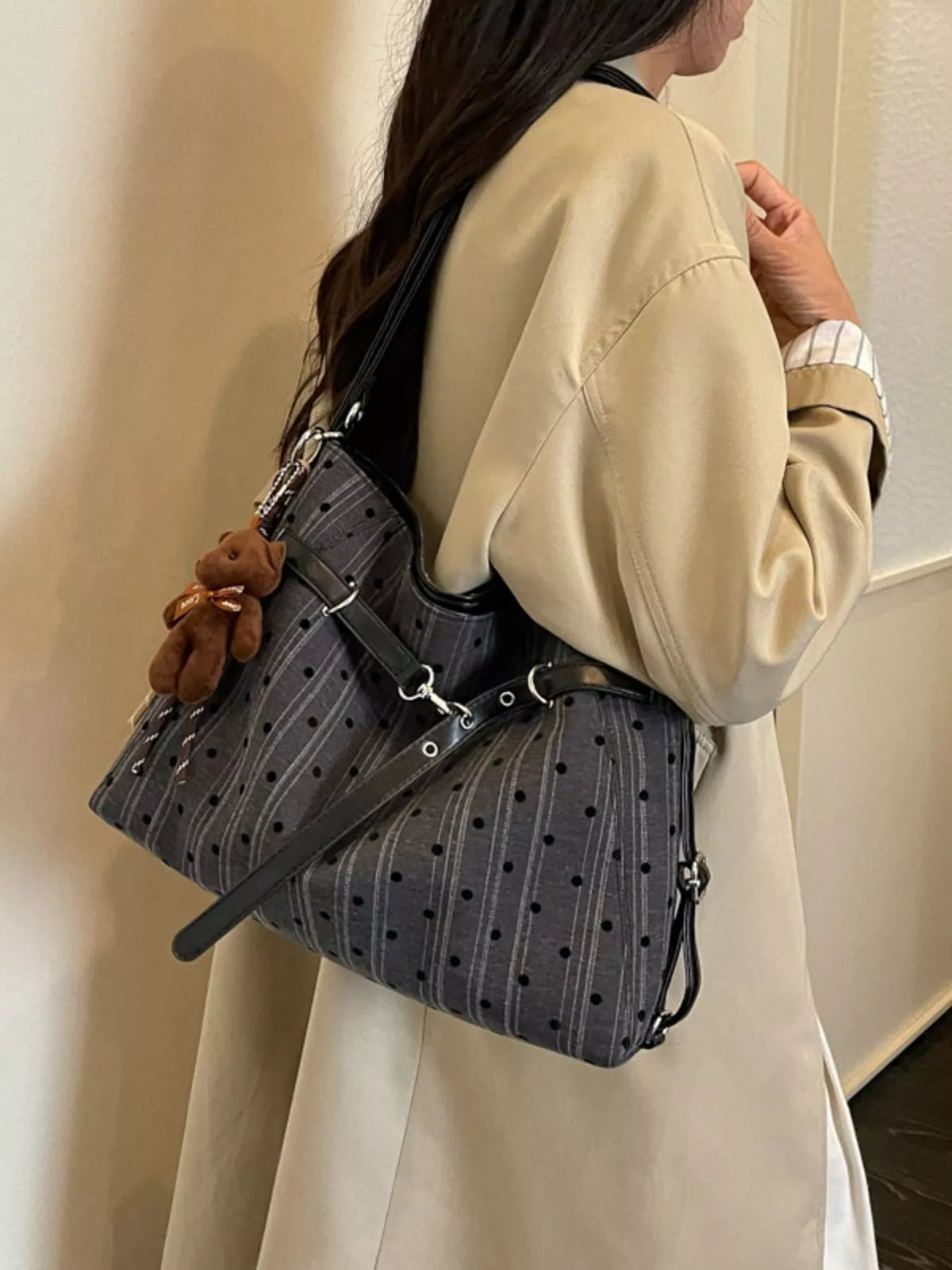 Dark polka dot canvas shoulder bag with top handle, adjustable strap, and zipper closure