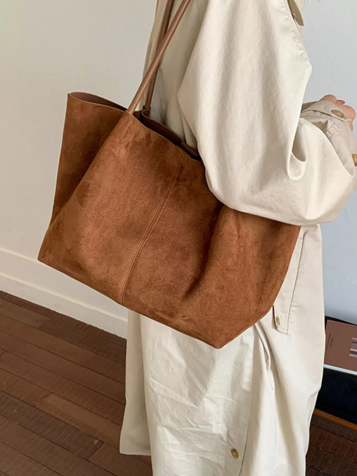 Brown suede large tote bag held by a person with shoulder-length handles