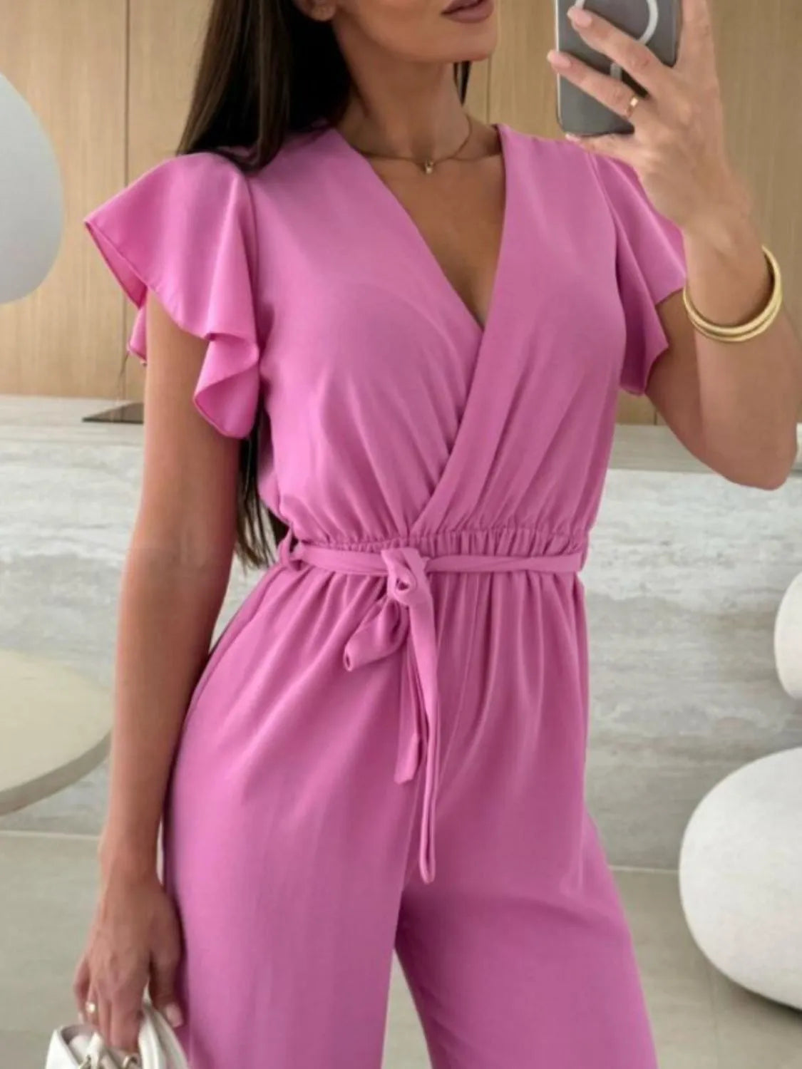 Fuchsia pink ruffled wide-leg jumpsuit with flutter sleeves and tied waist