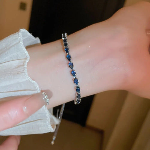 Royal blue beaded zircon bracelet on wrist, silver-tone chain and clasp