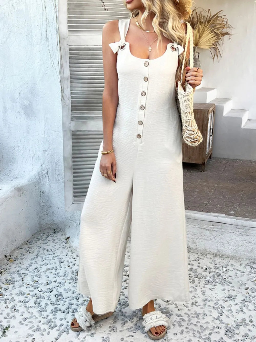 Cream sleeveless wide-leg jumpsuit with button front and knotted shoulder straps