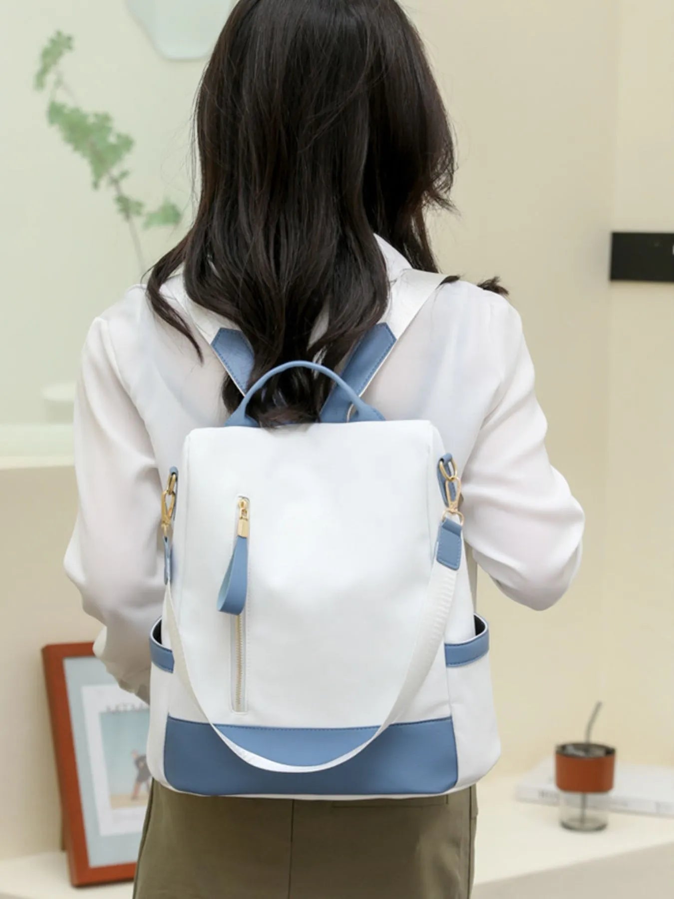 White and dusty blue color block convertible backpack bag worn on back with adjustable straps