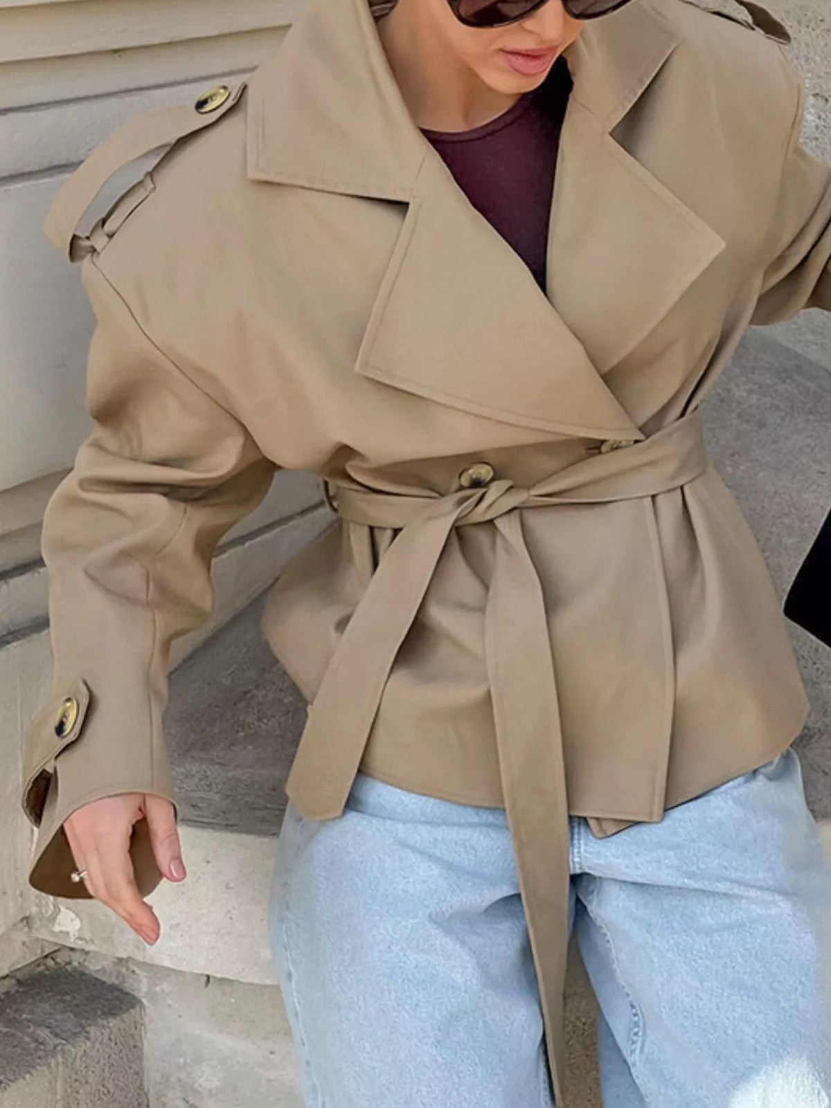 Khaki belted trench coat with double-breasted lapels and gold buttoned cuffs