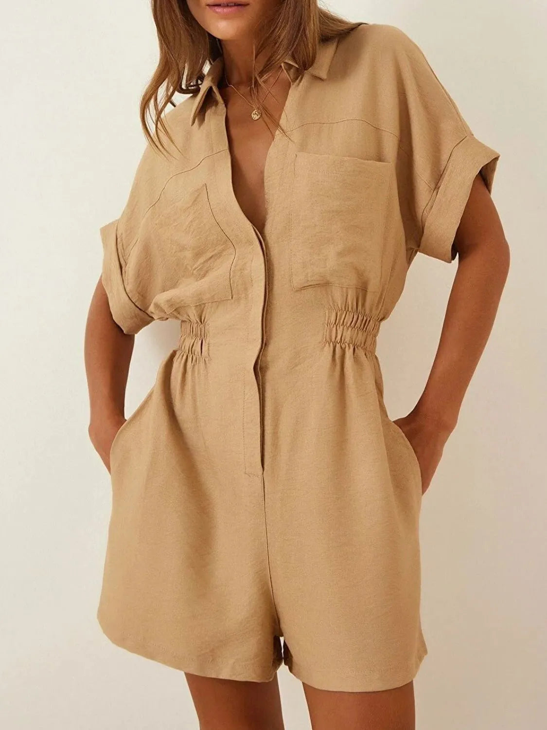 Tan short-sleeve romper with collar, button front, patch pockets, and elastic waist.
